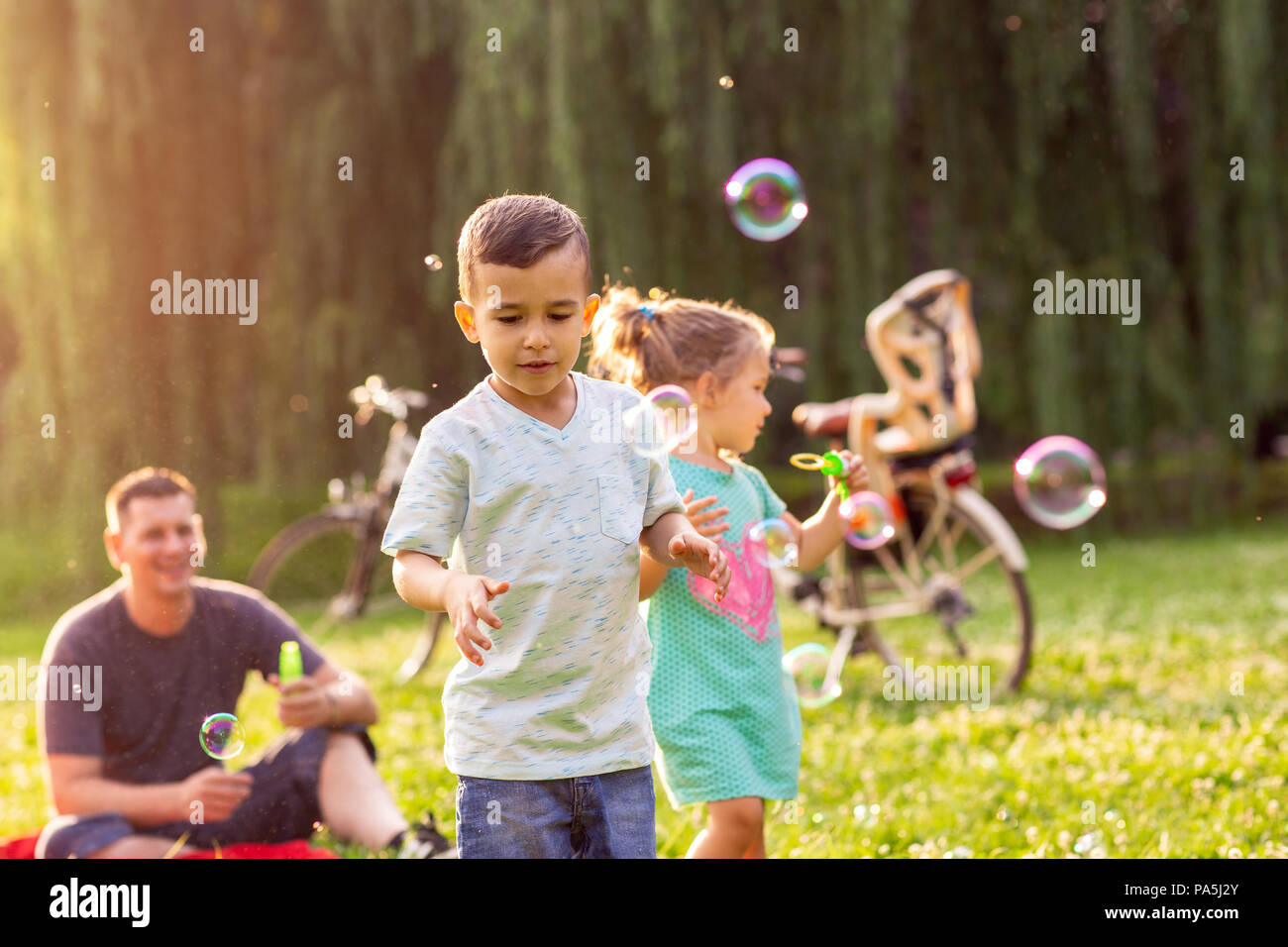 Zeit mit der Familie - Fröhlich niedliche Kinder chase Blasen in der Natur Stockfoto