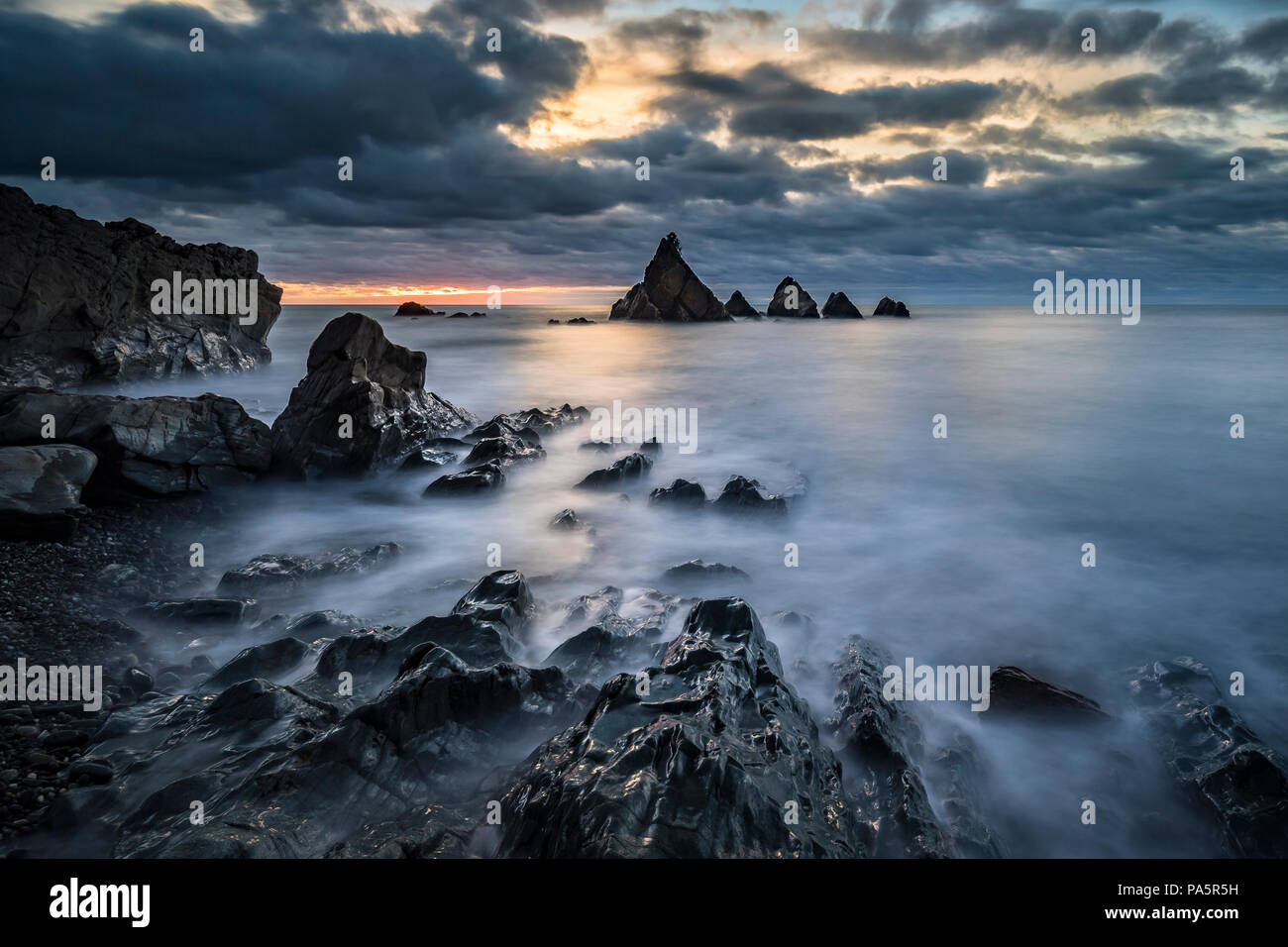 Zerbröckelt Küste bei Sonnenuntergang, Felsen im Meer, Cloud Stimmung, Greymouth, West Coast, South Island, Neuseeland Stockfoto