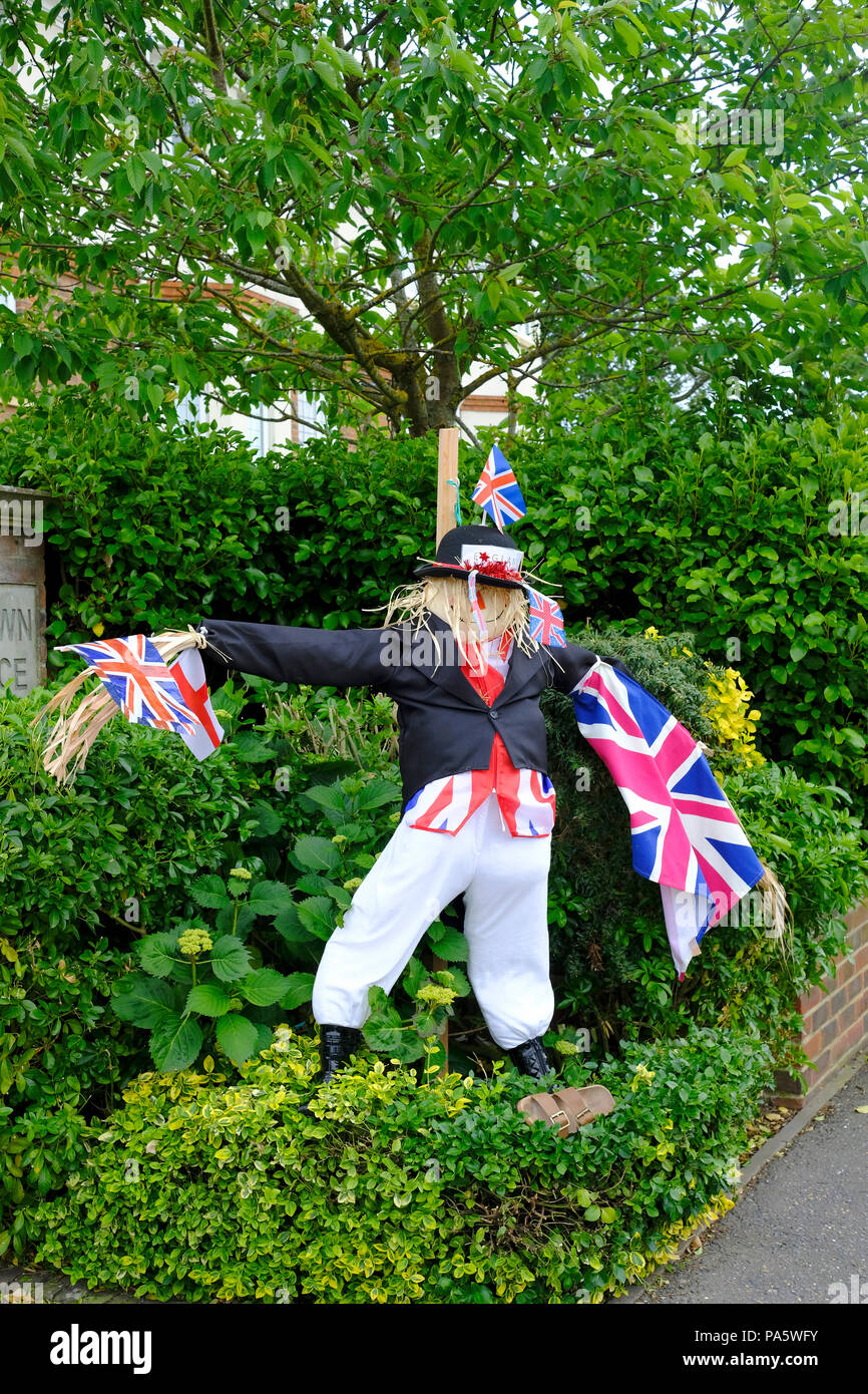 Männliche Vogelscheuche im Garten gekleidet, wie John Bull in dunklen Jacke und eine weiße Hose und halten Union Fahnen und England Flagge Stockfoto