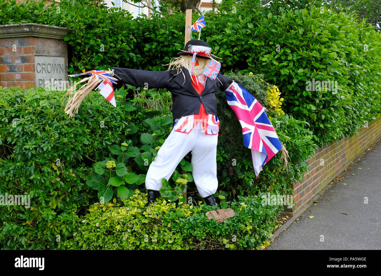 Männliche Vogelscheuche im Garten gekleidet, wie John Bull in dunklen Jacke und eine weiße Hose und halten Union Fahnen und England Flagge Stockfoto