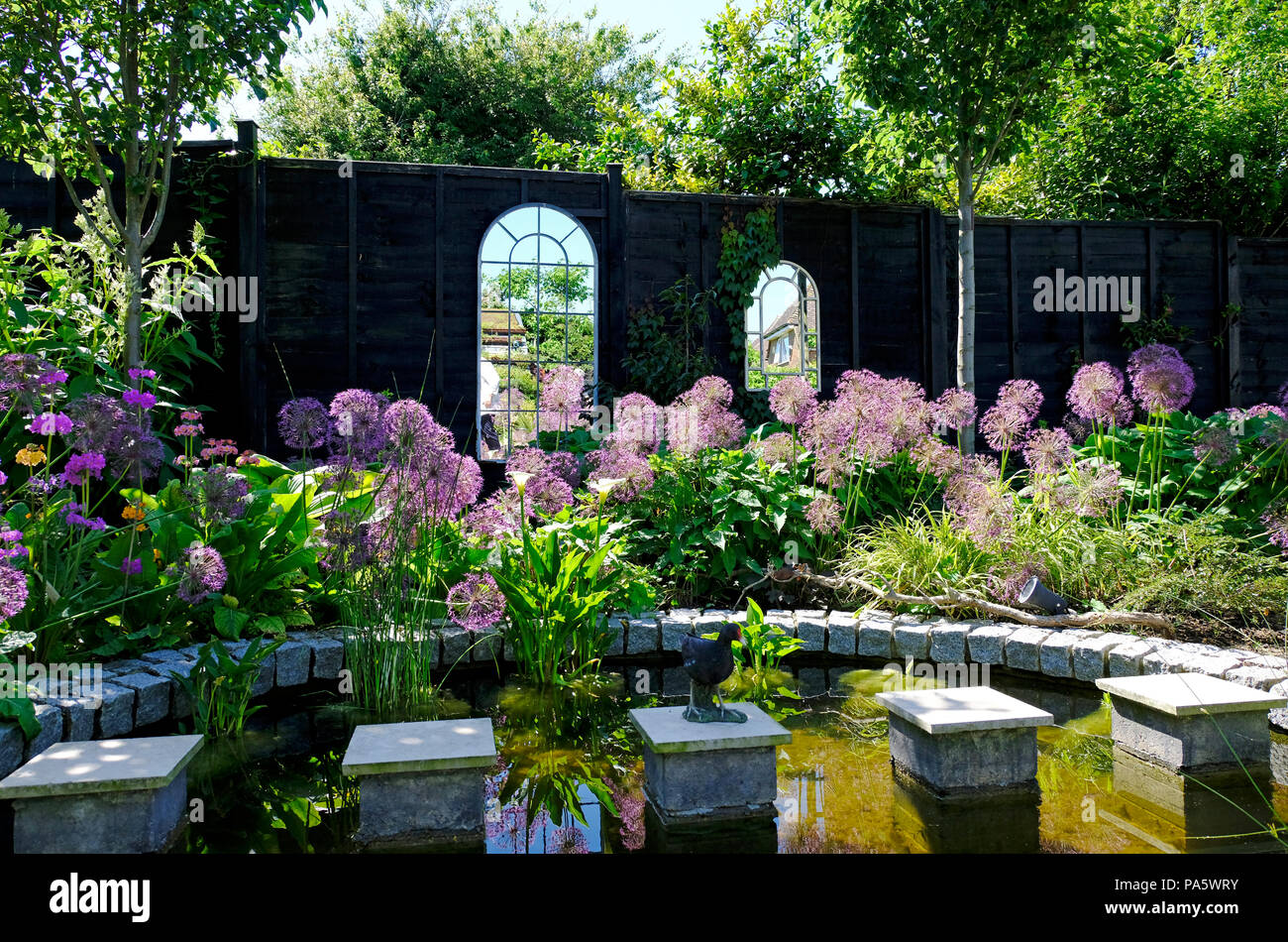 Garten Teich mit quadratischen Trittsteine und gespiegelte 'Windows' in den Zaun hinter gesetzt. Stockfoto
