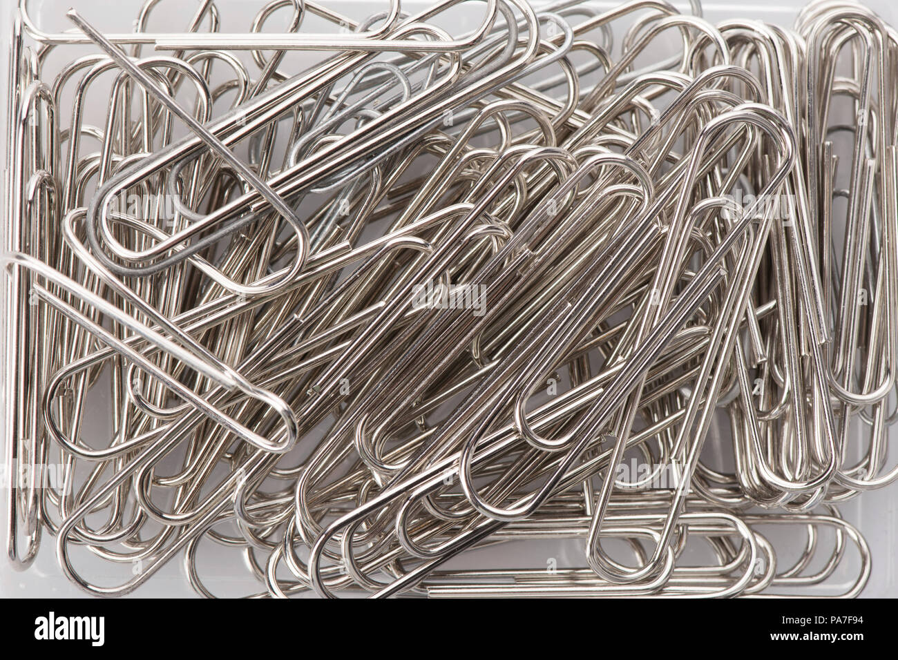 Viele Büroklammern verstreut auf Weiß. Stockfoto