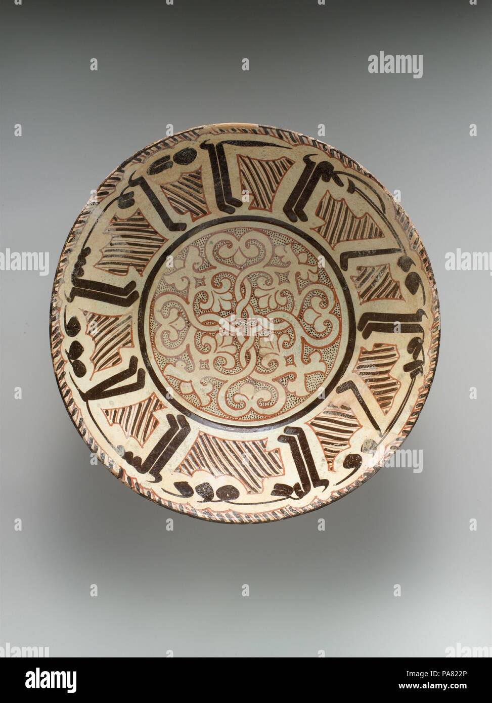 Schüssel mit arabischer Inschrift, "Segen, Wohlstand, Wohlbefinden, Glück'. Abmessungen: Max. Durchm. 14 in. (35,6 cm) H.4 1/4 (10,8 cm). Datum: Ende 10. bis 11. Jahrhundert. Viele Keramik aus der Region sind mit Kalligraphie nishapur eingerichtet. Das Schreiben auf diese Objekte bezieht sich oft auf ihre Verwendung (d. h. "Essen mit Appetit') oder ein bekanntes Sprichwort wiederholen. Das Schreiben auf diese Schüssel bringt gute Wünsche für die Eigentümer: "Segen, Glück, Wohlstand, Wohlbefinden, Glück." Neugierig, die Inschrift gehört das Starten eines weiteren Wortes, al, was bedeutet, dass "die", nicht aber den Rest des Wortes. Die hohen v Stockfoto