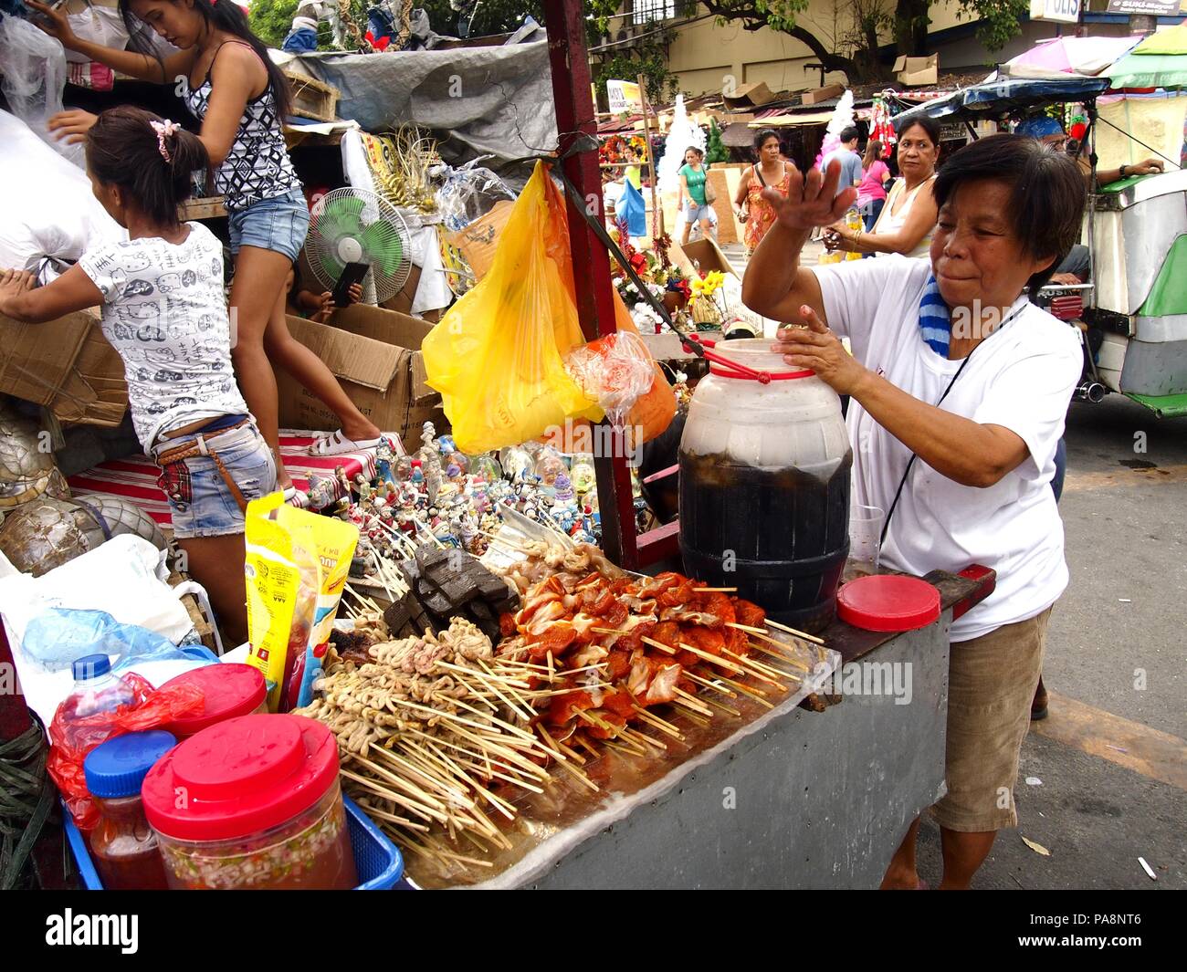 QUEZON CITY, Philippinen - 22. NOVEMBER 2015: eine Frau verkauft, kalte Säfte und eine große Auswahl an Grill auf einem Wagen auf einer Straße in Quezon City, Philippinen Stockfoto