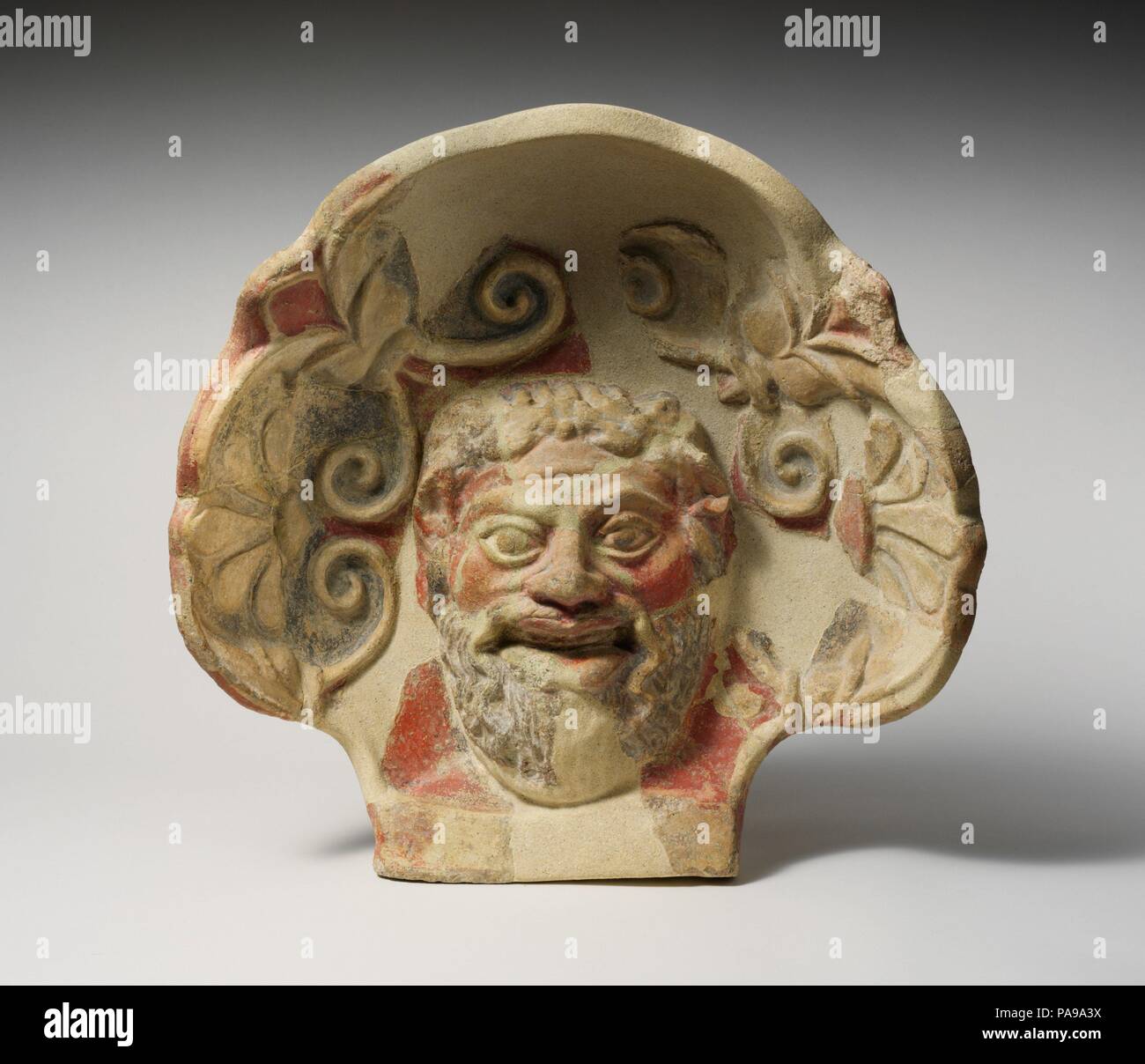 Terrakotta antefix (Dachziegel) mit dem Kopf eines Satyrs. Kultur: Etruskische, Cerveteri. Abmessungen: 19 9/16 x 19 5/8 in. (49,7 x 49,9 cm). Datum: 4. Jahrhundert v. Chr.. Auf Tempel Dächer, Satyr - Kopf antefixes oft wechseln sich ab mit maenad antefixes, wie 96.18.158. Sie sind in einer Shell - wie Hintergrund, mit palmetten und Lotus Blüten dekoriert. Museum: Metropolitan Museum of Art, New York, USA. Stockfoto