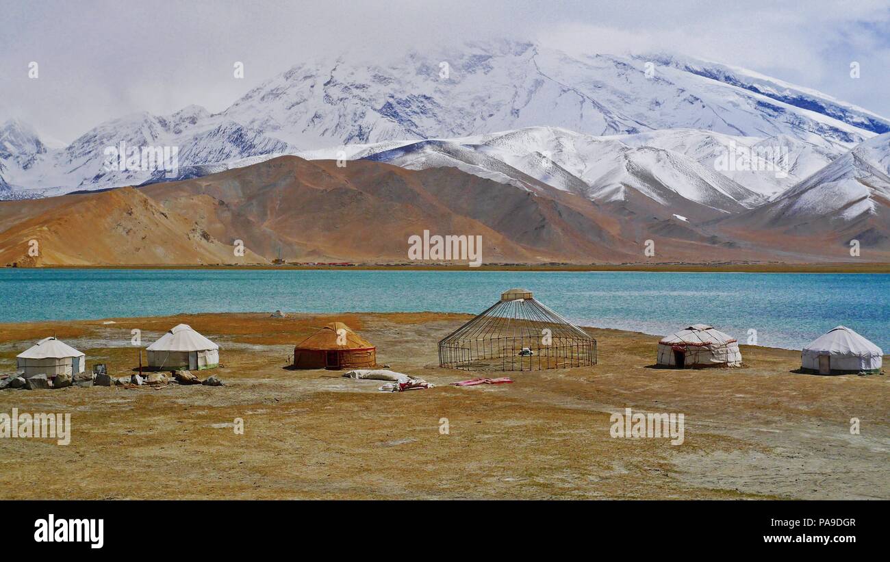 Chinesische nomadischen Gehäuse der Minderheit am Karakul See in Xinjiang mit schneebedeckten Bergen im Hintergrund. Stockfoto