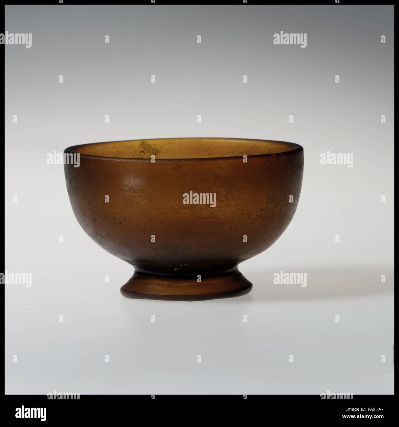 Glasschale. Kultur: Griechisch. Abmessungen: H.: 2 5/8 x 3 3/4 in. (6,7 x 9,5 cm). Datum: 1. Jahrhundert v. Chr.. Translucent deep golden braun. Vertikale rim mit der abgerundeten Kante; konvex geschwungene Seite verjüngt sich nach unten, um die flachen Boden innerhalb der Integral outsplayed, leicht oval Base Ring mit dicken abgerundeten Kante. Intakt; einige pinprick Blasen, ein paar größere Blasen und Streifen; Mattierung, Lochfraß, und schwache Schillern. Rotary Schleifspuren auf Interieur und Exterieur. Museum: Metropolitan Museum of Art, New York, USA. Stockfoto