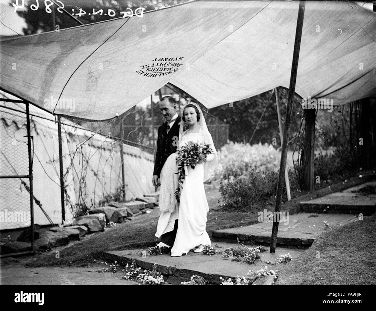 235 SLNSW 10206 Paar Ankunft am Festzelt unter Leinwand Schutz vor dem Regen WhitneyFriend Hochzeit Stockfoto