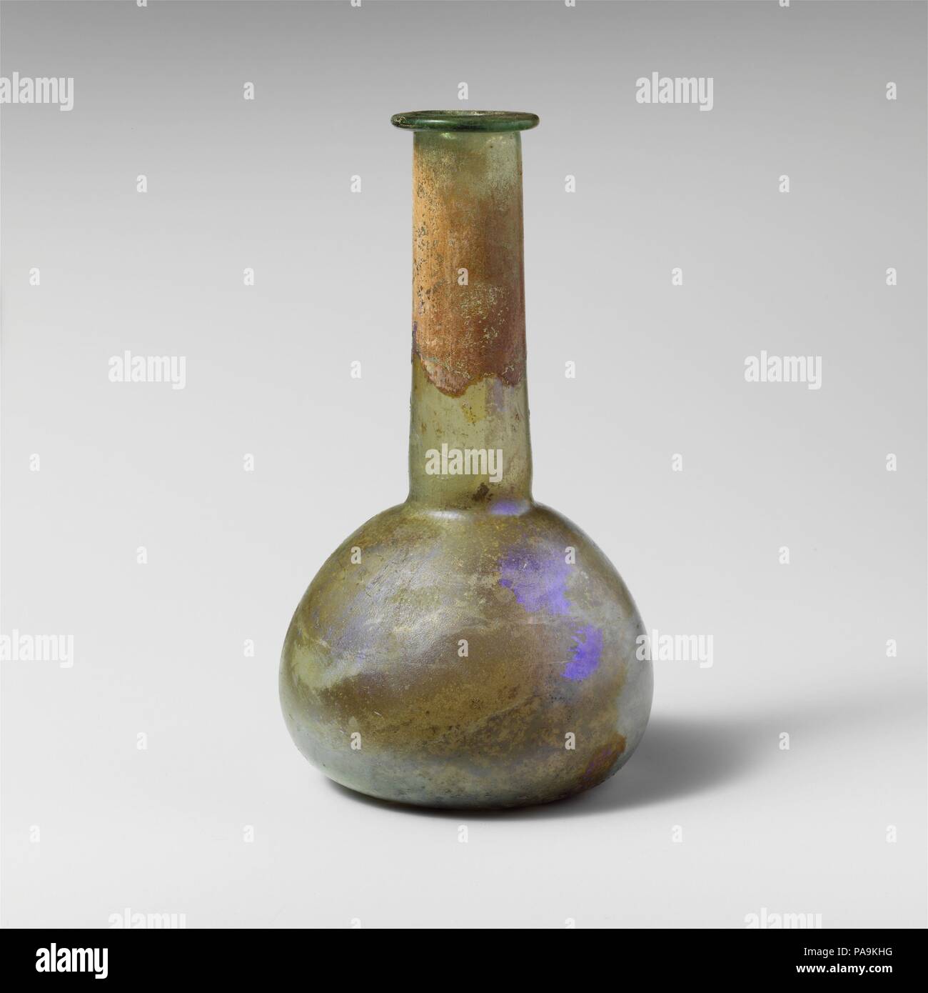 Glas Parfüm Flasche. Kultur: Roman. Abmessungen: Insgesamt: 6 1/16-in. (15,4 cm) Durchm.: 3 1/2 x 1 5/16 in. (8,9 x 3,3 cm). Datum: 2.-3.Jh. N.CHR.. Translucent Hellblau grün. Rim ausgeklappt, über, in, auf und bilden eine leichte Verengung in den Mund abgeflacht; zylindrische Hals, Erweiterung leicht nach unten, mit nachgerüstet Gedankenstrich um Base; bauchigen Körper; flachen Boden. Intakt; pinprick Blasen und blasen Streifen; Mattierung, Lochfraß und irisierenden Verwitterung, mit Erde Kühlmitteldurchlauf im Innenbereich an. Museum: Metropolitan Museum of Art, New York, USA. Stockfoto