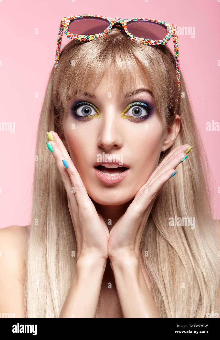 Junge blonde Frau mit Spaß Süßigkeiten Brille auf die Stirn. Porträt von Frauen in lila Kleid mit blauen und gelben Augen Make-up. Stockfoto
