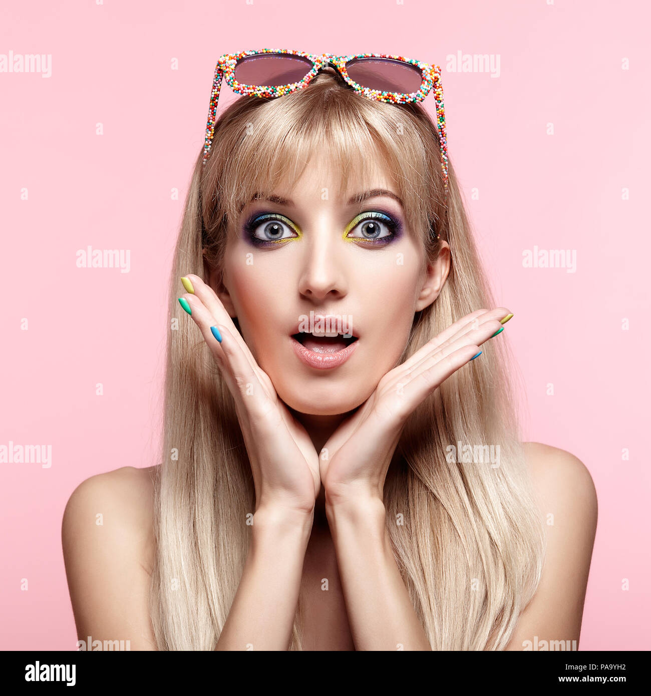Junge blonde Frau mit Spaß Süßigkeiten Brille auf die Stirn. Porträt von Frauen in lila Kleid mit blauen und gelben Augen Make-up. Stockfoto