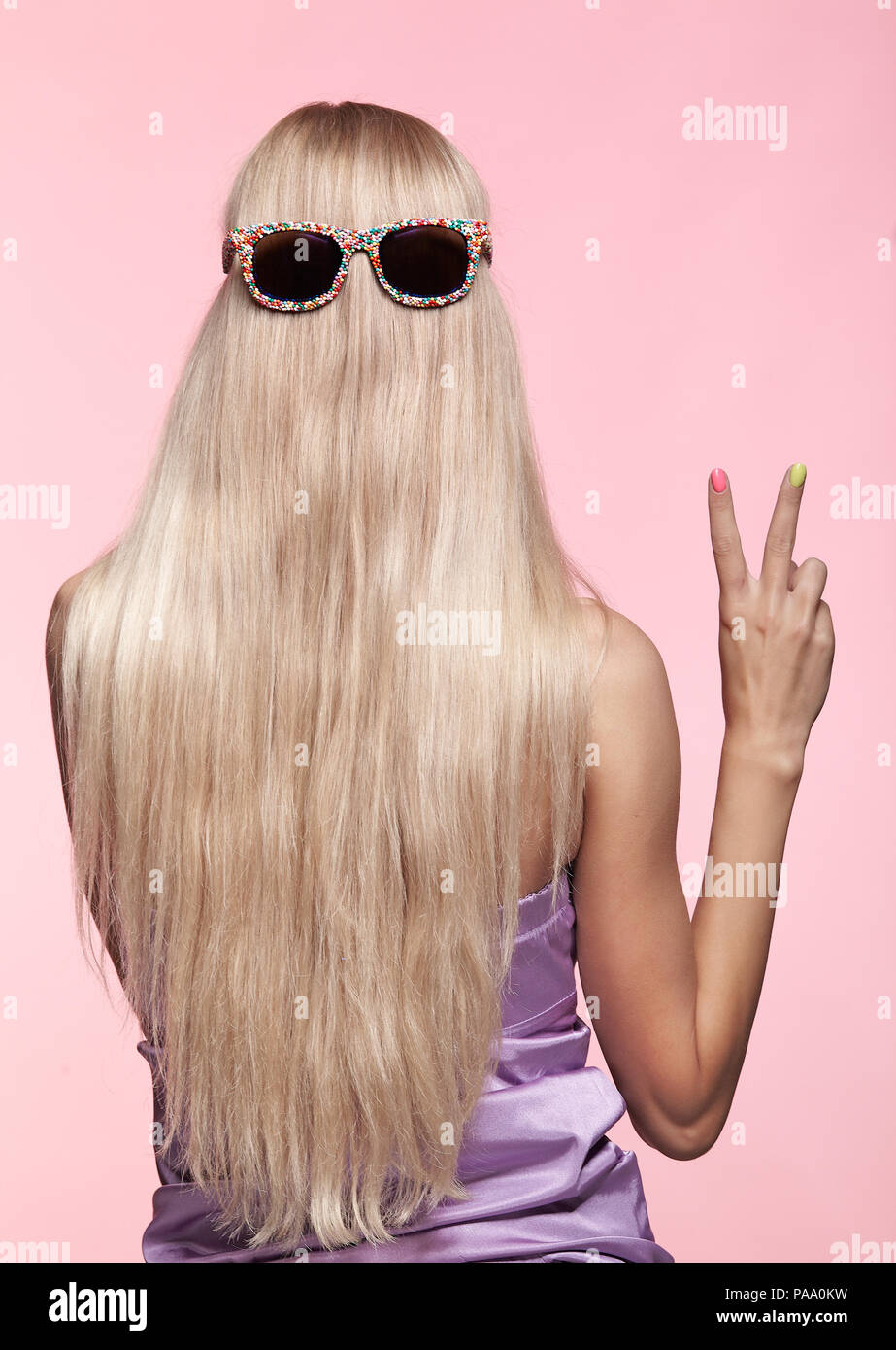 Ansicht der Rückseite des jungen Frau. Blond stright Haar mit Spaß Sonnenbrille. Weiblichen finger Nägel mit hellen Maniküre Stockfoto