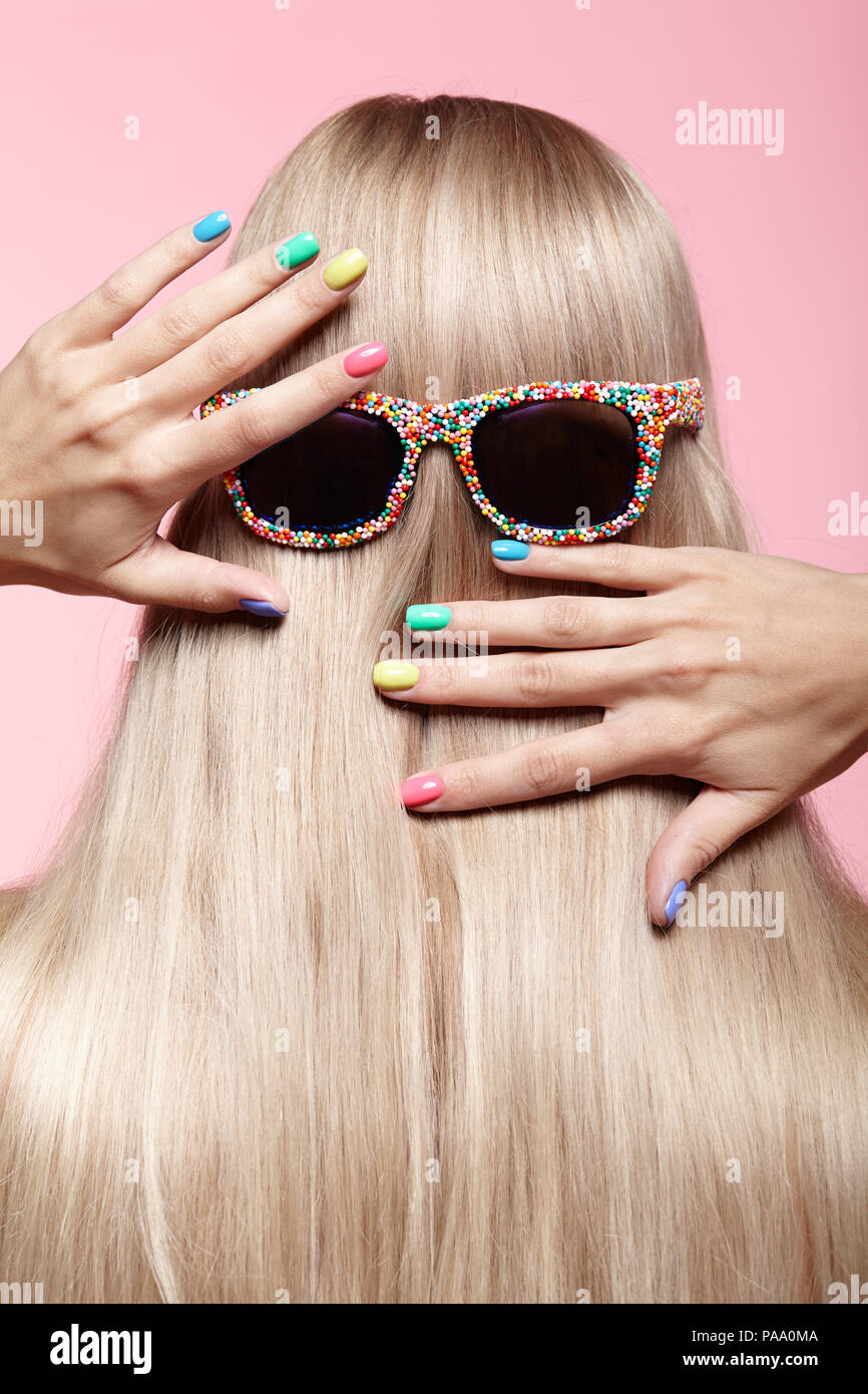 Ansicht der Rückseite des jungen Frau. Blond stright Haar mit Spaß Sonnenbrille. Weiblichen finger Nägel mit hellen Maniküre Stockfoto