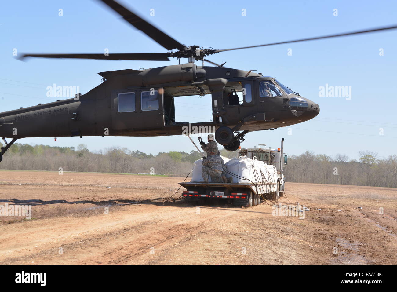 Louisiana National Guard Soldaten des 225Th Engineer Brigade verbinden 1.500 Pfund super Säcke zum Ende einer UH-60M Black Hawk zu schleudern werden von Piloten aus der Army Aviation Support Facility Nr. 3 in Pineville, La geladen, in Bayou Darrow südlich von Colfax in Grant Parish, La Die super Säcke werden verwendet, um den Fluss von Wasser, bei denen eine Steuerung fehlgeschlagen zu verlangsamen, 14. März 2016. Mehr als 1.400 Gardisten haben die Flut kämpfen über Louisiana unterstützt. (U.S. Army National Guard Foto von 1 Lt. Rebekka Malone) Stockfoto