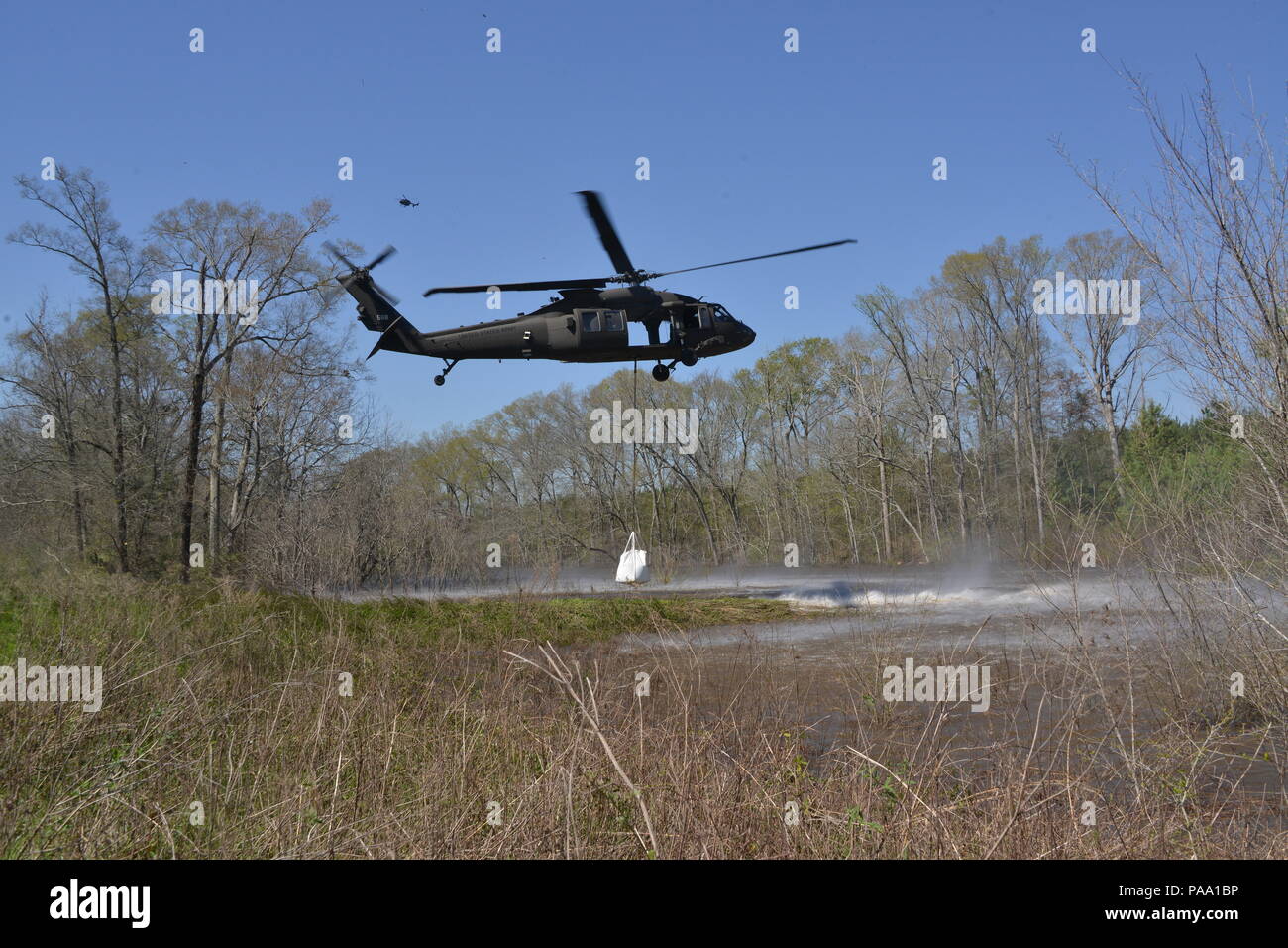 Louisiana National Guard Soldaten des 225Th Engineer Brigade verbinden 1.500 Pfund super Säcke zum Ende einer UH-60M Black Hawk zu schleudern werden von Piloten aus der Army Aviation Support Facility Nr. 3 in Pineville, La geladen, in Bayou Darrow südlich von Colfax in Grant Parish, La Die super Säcke werden verwendet, um den Fluss von Wasser, bei denen eine Steuerung fehlgeschlagen zu verlangsamen, 14. März 2016. Mehr als 1.400 Gardisten haben die Flut kämpfen über Louisiana unterstützt. (U.S. Army National Guard Foto von 1 Lt. Rebekka Malone) Stockfoto