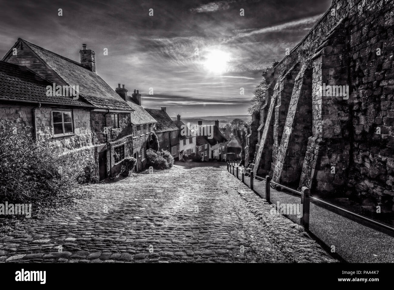 Schwarz & Weiß des berühmten Gold Hill in Shaftesbury mit Sonne im Himmel in Shaftebury, Dorset, Großbritannien am 3. Januar 2017 getroffen Stockfoto