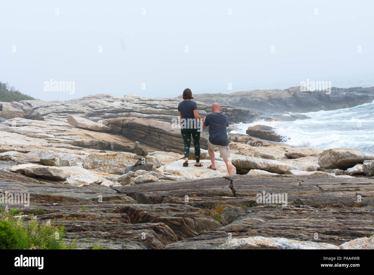Ein paar macht ihren Weg entlang der felsigen Küste von Maine im Ocean Point in Boothbay, Maine, USA Stockfoto