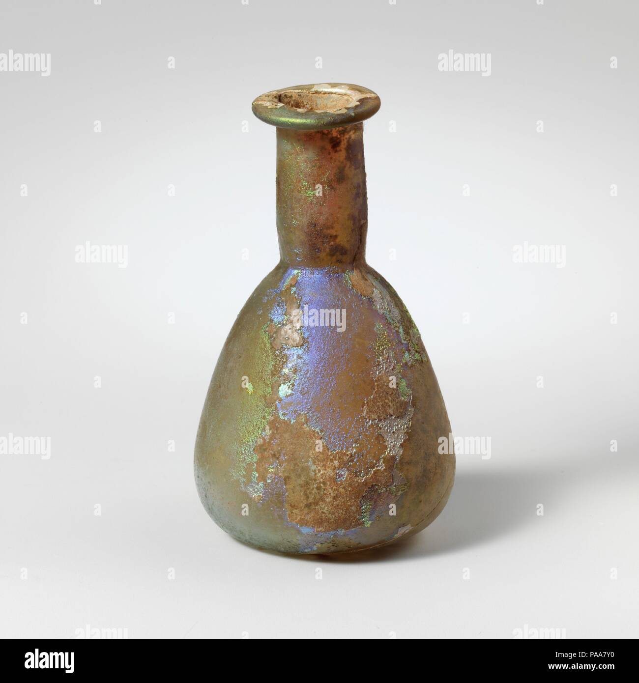 Glas Parfüm Flasche. Kultur: Roman. Abmessungen: 2 15/16 in. (7,4 cm) Durchmesser: 1 3/4 x 7/8 in. (4,4 x 2,2 cm). Datum: 1. Jh. N.CHR.. Farblos mit hellen blau-grüne Färbung. Schiefe rim ausgeklappt, über, und in, und drückte flache, zylindrische Hals, mit schnittspuren um Base; konischen Körper mit konvexen Seiten; flachen Boden. Komplette, aber große Sprung von rimto unten; pinprick blasen; Mattierung, Lochfraß, und brillante irisierende Verwitterung. Museum: Metropolitan Museum of Art, New York, USA. Stockfoto
