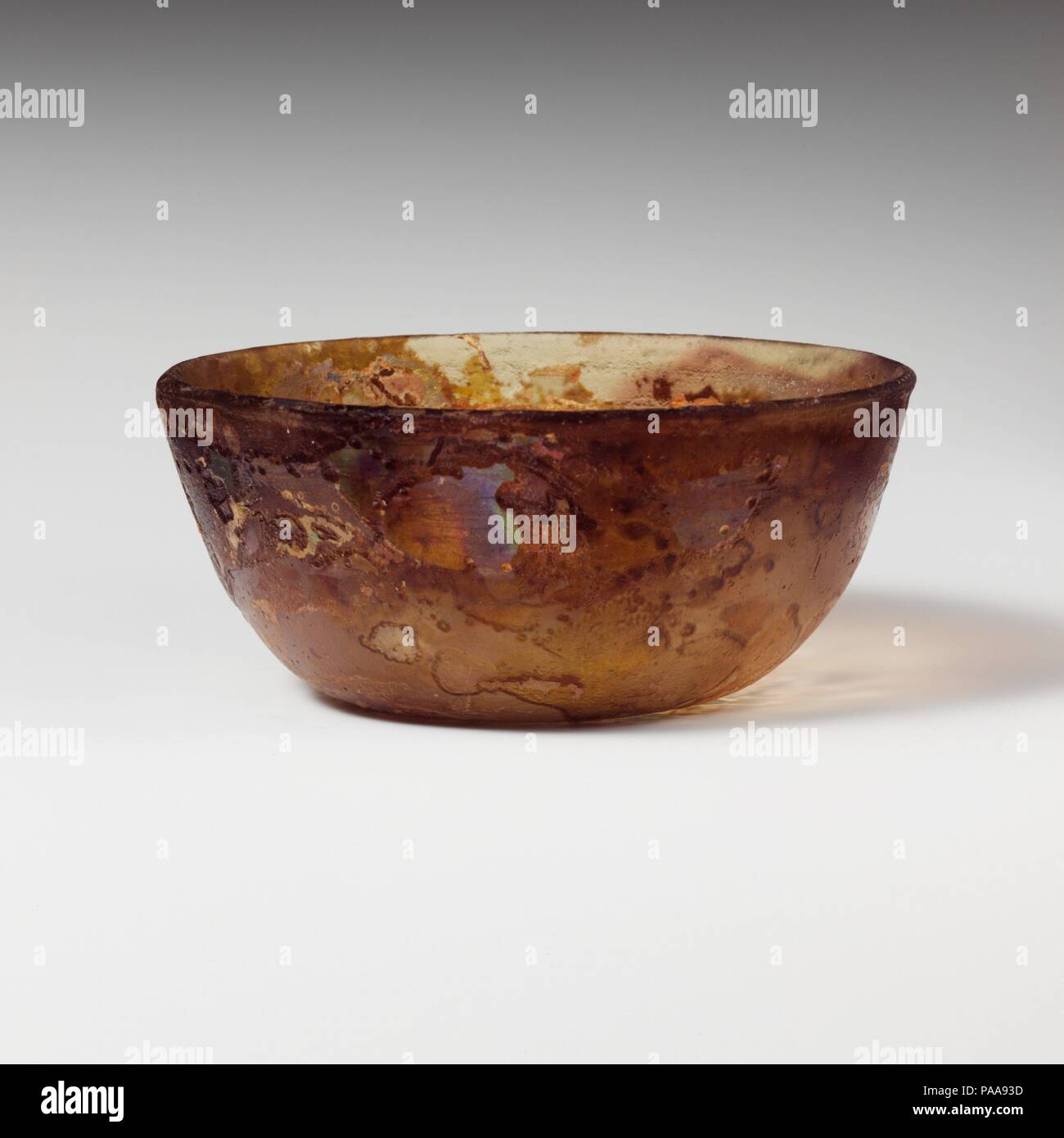 Glasschale. Kultur: Roman. Abmessungen: H.: 2 1/16-in. (5.2 cm) Durchm.: 4 5/8 in. (11,7 cm). Datum: Ende 1.Jh. v. Chr. - frühe 1. Jh. N.CHR.. Farblos mit hellgelben Farbton und purpurfarbenen Streifen Abgerundet vertikale Rim; leicht konvexe Seiten, verjüngt sich nach unten; flachen Boden. Zwei breite horizontale Rad - Nuten auf der Innenseite unten Rim schneiden. Intakt; ein Paar pinprick blasen; tiefe Rillen, Mattieren, und irisierenden Verwitterung. Museum: Metropolitan Museum of Art, New York, USA. Stockfoto