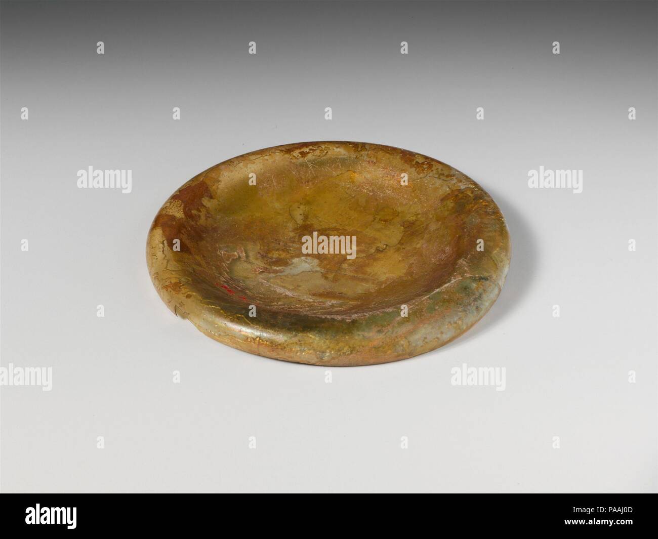 Glas Deckel. Kultur: Roman, der Zyprischen. Abmessungen: 1,1 cm. (1.1 cm) Durchmesser: 2 15/16 in. (7,5 cm). Datum: 2.-3.Jh. N.CHR.. Farblos mit grünlichen Farbton. Klopfte, invertiert Lippe; abgerundete Kante; breit, konkav nach oben. Intakt, außer für Verluste Teil der Lippe; Nadelstich und große Blasen; tiefe Verwitterung und brillante Schillern; einige rote Erde Verkrustung auf der Innenseite unter der Lippe. Museum: Metropolitan Museum of Art, New York, USA. Stockfoto