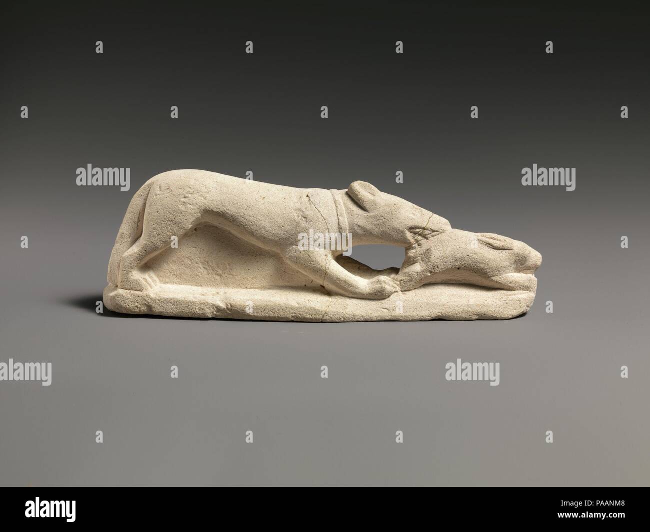 Kalkstein Statuette eines Coursing Hund fressen einen Hasen. Kultur: Zypriotische. Abmessungen: Insgesamt: 2 1/4 x 6 1/2 x 1 1/8 in. (5,7 x 16,5 x 2,9 cm). Datum: Ca. 5. oder 4. Jahrhundert v. Chr.?. Eine schlanke Hound, trägt ein Halsband, ergreift einen Hasen von der Hinterhand. Museum: Metropolitan Museum of Art, New York, USA. Stockfoto