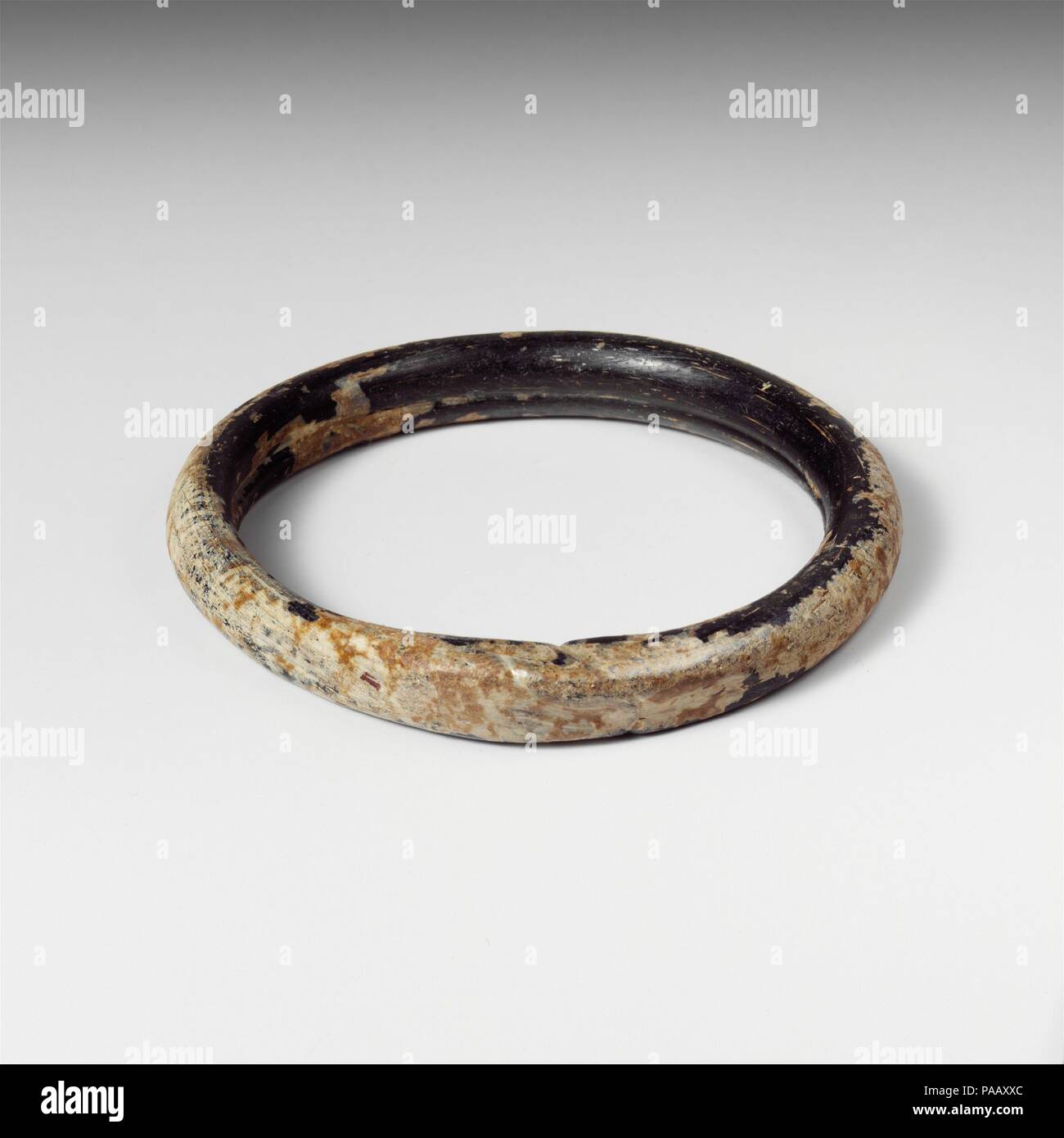 Glas Armband. Kultur: Roman. Abmessungen: H.: 1/2 in. (1,3 cm) Durchm.: 3. 7,6 cm (3 Zoll). Datum: Ca. 2.-4.Jh. N.CHR.. Transluzente sehr dunkel Grün, erscheint schwarz. Kreisförmige Band; runde in Abschnitt aber mit Nut um innere Seite; in quadratischen Abschnitt an der Nahtstelle, wo die Enden der Stange mit unregelmäßigen Schnittspuren gedrückt wurden abgeflacht; kleine pontil Narbe am äußeren Rand der gegenüberliegenden Seite. Intakt; längliche blasen; Mattierung, schwachen Schillern und Patches von dicken, cremigen Verwitterung. Museum: Metropolitan Museum of Art, New York, USA. Stockfoto