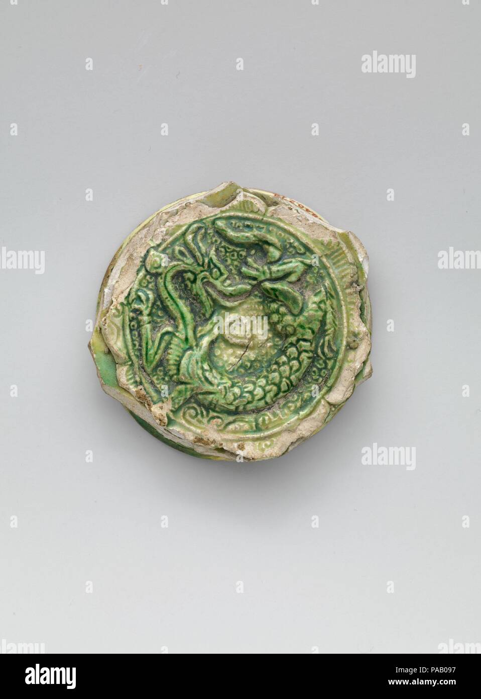 Fragment eines importierten Chinesischen Schüssel. Abmessungen: 2 5/8 in. (6,7 cm). Datum: Ende im 7. Halbjahr 8. Chinesische Keramiken wurden sehr geschätzt und in der Regel in Nishapur imitiert. Die nishapur Imitationen nahm verschiedene Formen: die Weiße der chinesischen Porzellan führte lokale Töpfer das opake, weiße Glasuren, mit denen sie ihre Waren zu entwickeln, während der drei Farben sancai chinesischen Einfuhren führte zur Erfindung von splashware, tropft, braun, gelb, und grün Glasuren über ihre Töpfe. Dieses Medaillon von der Basis aus einer Schüssel, mit der geformten Bild von einem Drachen mit einem flammenden Juwel, Stockfoto