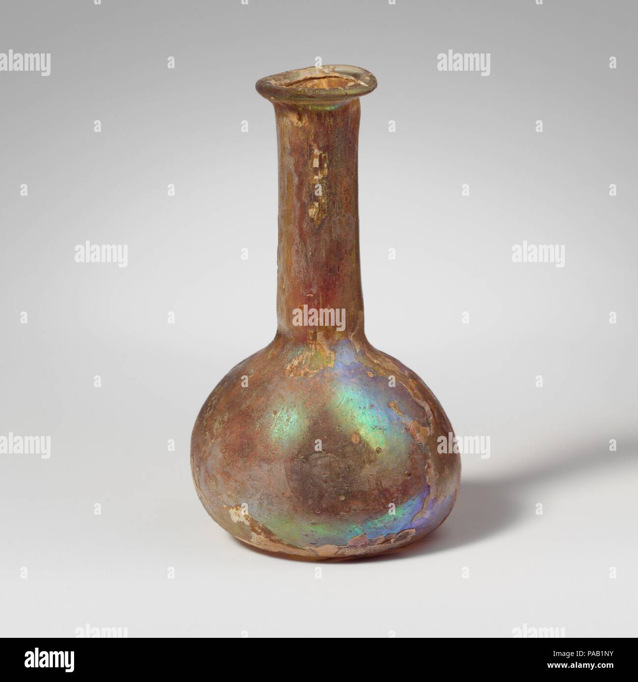 Glas Parfüm Flasche. Kultur: Roman. Abmessungen: 4 1/2 in. (11,5 cm) Andere: 2 5/8 in. (6,7) Durchm. Von rim: 1 3/16 in. (3 cm). Datum: 2.-3.Jh. N.CHR.. Farblos. Ungleichmäßige, abgerundete Kante, Ausgeklappt, über, und in; zylindrische Hals, leicht erweitern in der Nähe von Basis, und Schnittspuren um Base; Hocke, bauchigen Körper; flache Unterseite mit der abgerundeten Kante. Intakt; viele Blasen und blasen Streifen; tiefe Rillen und brillante irisierende Verwitterung. Museum: Metropolitan Museum of Art, New York, USA. Stockfoto