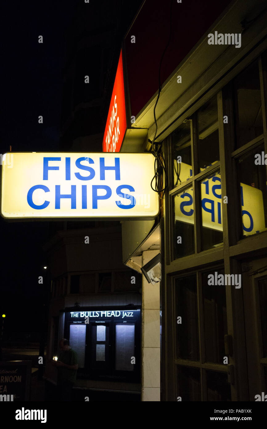 Eine beleuchtete Fish und Chips Zeichen außerhalb einen Fisch und Chip Shop in London, Großbritannien Stockfoto
