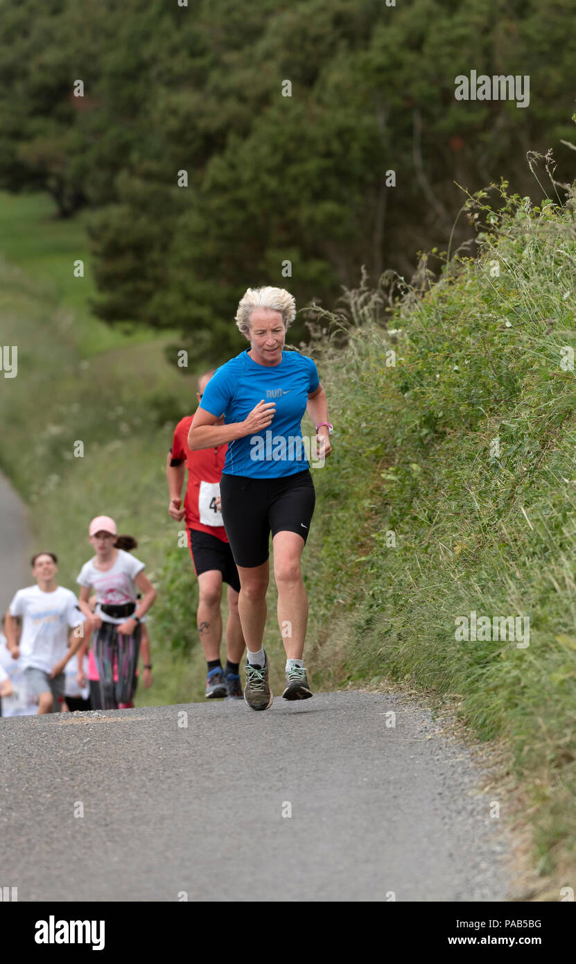 Frau ein blaues Hemd in einem Spaß in einem Devonshire Dorf laufen Laufbekleidung Stockfoto