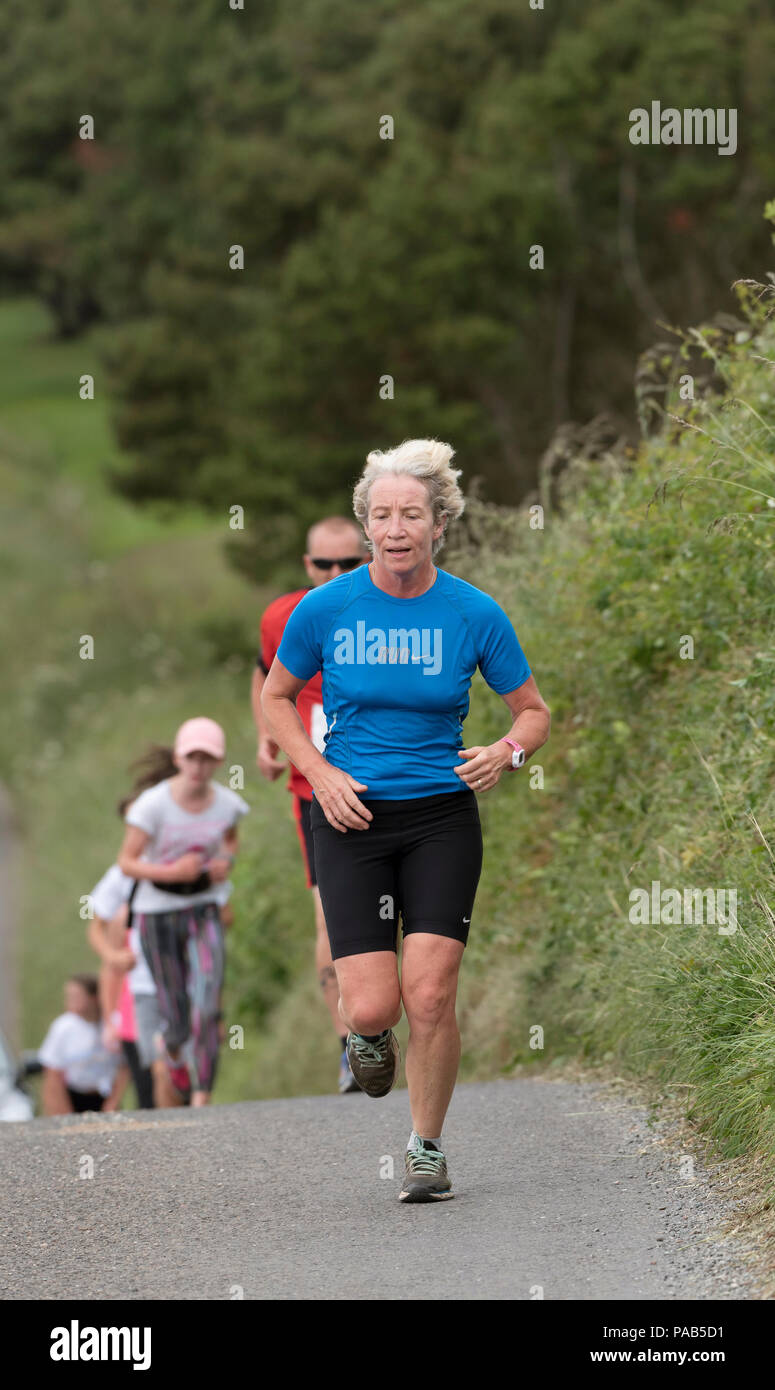 Frau ein blaues Hemd in einem Spaß in einem Devonshire Dorf laufen Laufbekleidung Stockfoto