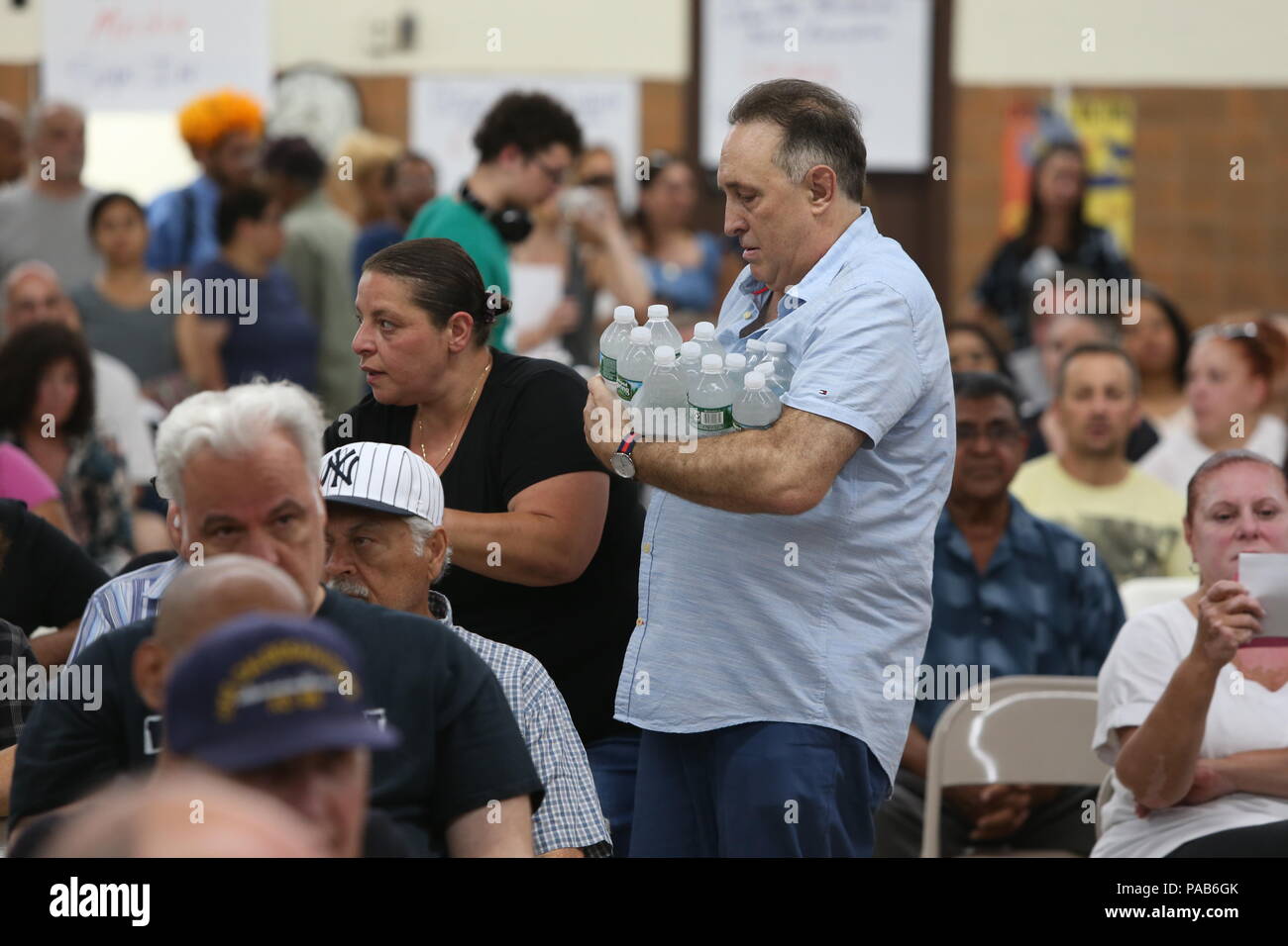 New York City, USA. 19. Juli 2018. Sam Esposito fließt das Wasser für die Bewohner während der Anhörung. Ozon Park, Queens Bewohner versammelt in der Geburt der seligen Jungfrau NYC Abteilung der heimatlosen Service Personal über den Plan der Abteilung eine Notunterkunft für 113 psychisch Kranke obdachlose Männer in stillgelegten Gebäude der Kirche in ihrer Nachbarschaft zu erlassen zu konfrontieren. Bewohner behaupten Rathaus ohne Warnung oder Eingabe von jedermann in der Ozonschicht Park Gemeinschaft gehandelt. Credit: Andy Katz/Pacific Press/Alamy leben Nachrichten Stockfoto