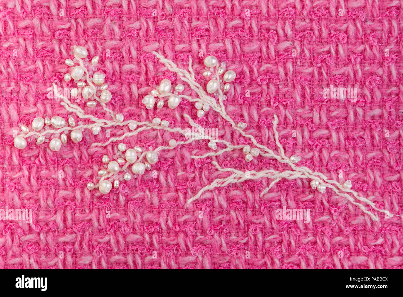 Pearl Zweig mit Knospen Stickerei auf fuchsia Tweed clouseup Stockfoto