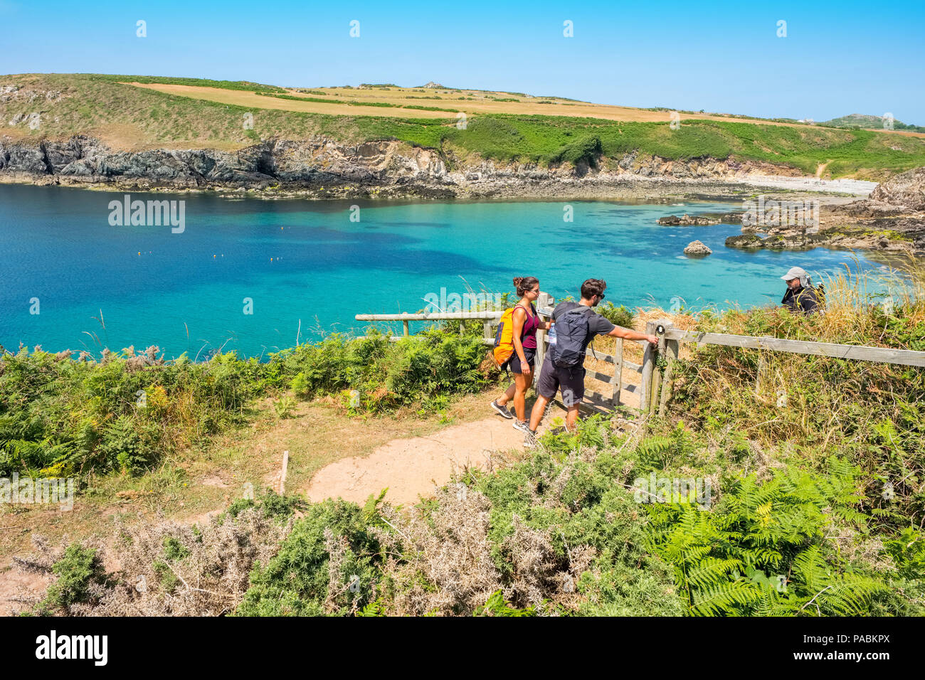 Junges Paar zu Fuß auf den Pembrokeshire Coast Path an Porthlysgi Bay in der Nähe von St Davids, West Wales Stockfoto