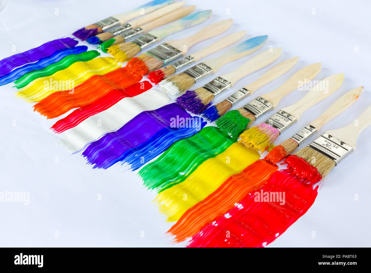 Reihe von Pinseln mit bunten Farben in parallelen Streifen in den Farben des Spektrums oder Regenbogen in einer diagonalen Linie auf weißem Papier mit c Stockfoto