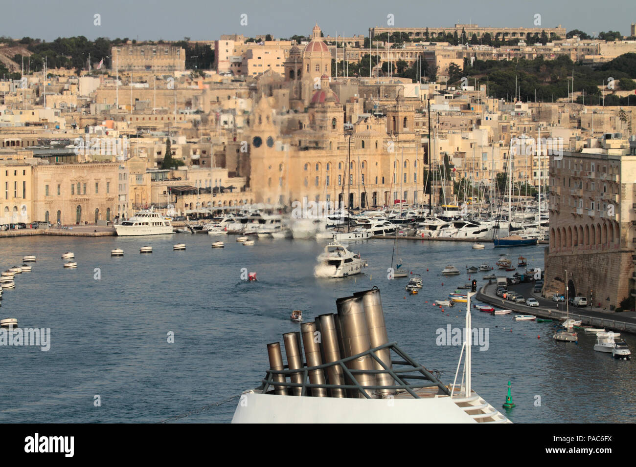 Sauberer Auspuff aus dem Schornstein eines Kreuzfahrtschiffes sichtbar vor dem Hintergrund von Birgu in Malta. Kohlenstoffemissionen von Schiffen und globale Erwärmung. Stockfoto