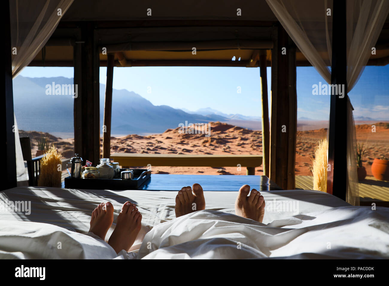 Paar im Bett Faulenzen auf Hochzeitsreise mit Vista Ansicht der Namib auf wolwedans Lodge Stockfoto