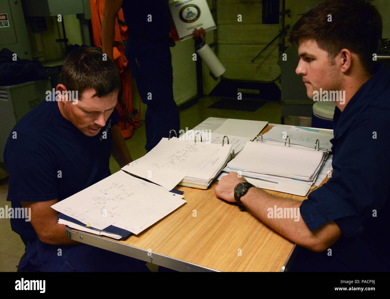 Als Teil seiner Beschädigung der Qualifikation, Feuerwehrmann Lehrling Ryan Finn (rechts) Bewertungen Zeichnungen der an Bord Brandbekämpfung System mit Petty Officer 1st Class George Grant, ein bootsmann mate, auf der messdeck der USCGC Kukui (WLB 203), 12. März 2016. Alle Personen an Bord des Schiffes sind erforderlich zur qualifizierten, so dass im Notfall sie können entsprechend reagieren werden. (U.S. Coast Guard Foto von Petty Officer 2. Klasse Melissa E. McKenzie/Freigegeben) Stockfoto