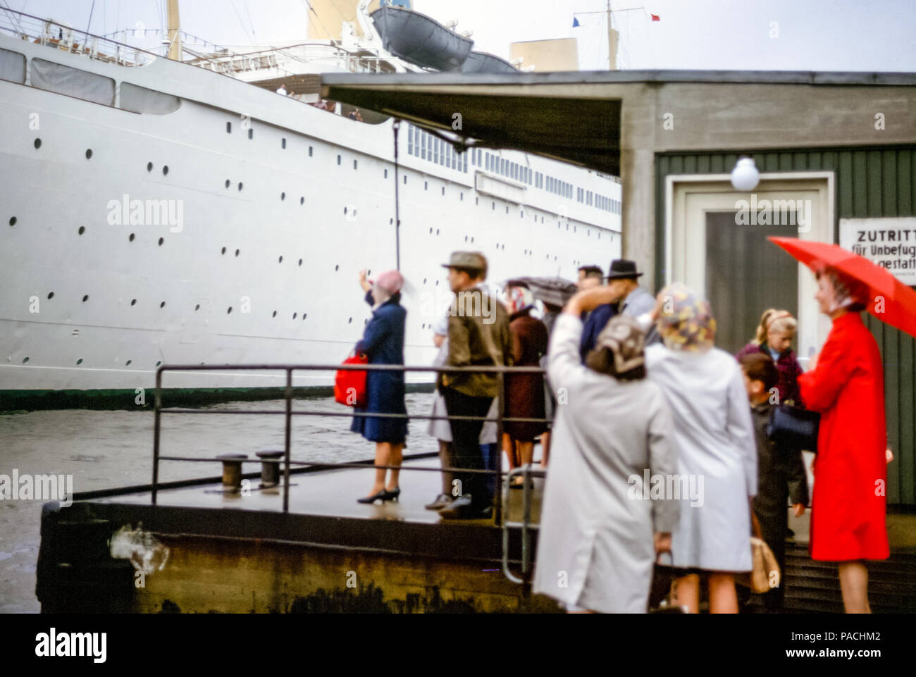 Menschen winken Auf Wiedersehen zu Passagieren auf einem Ozeandampfer auf der Elbe an einem regnerischen Tag, Hamburger Hafen, Deutschland in den 1960er Jahren Stockfoto