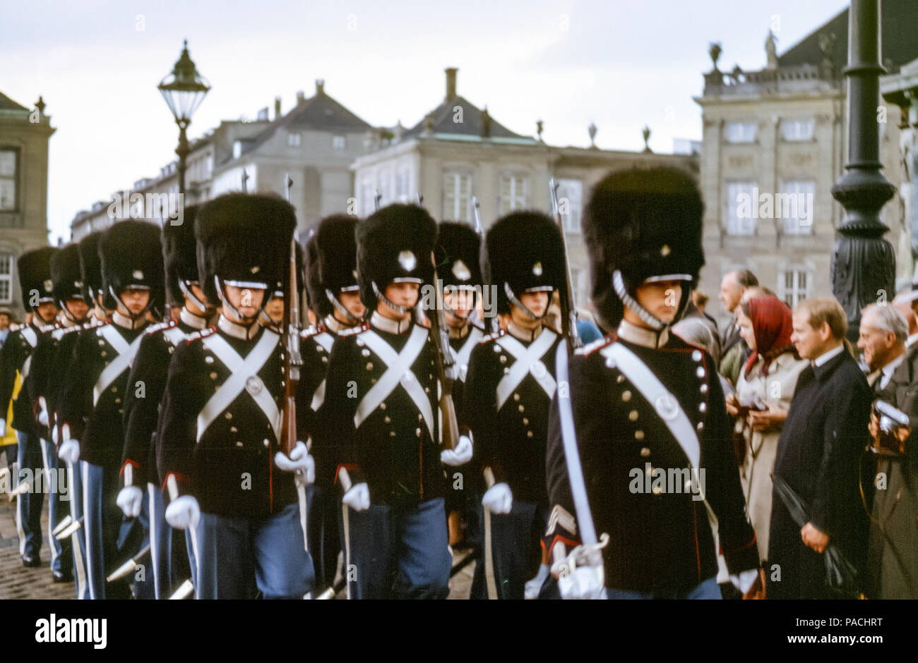 Touristenmassen beobachten die dänische Kaisergarde in Uniformen und Bärenfellhüten mit Gewehren, die bei der Wachablösung im Schloss Amalienborg, Kopenhagen, Dänemark in den 1960er Jahren marschieren Stockfoto