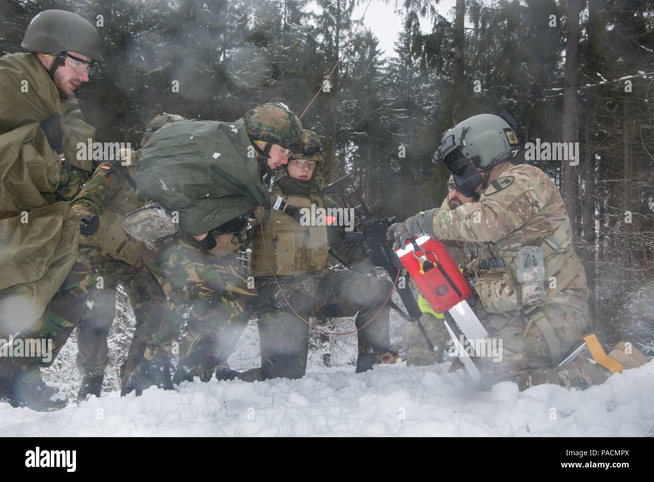 Deutsche Soldaten unterstützen ein internationales Soldat, Role player, mit simulierten Schusswunden für Evakuierung aus dem Schlachtfeld mit einem Dschungel penetrator und ein Black Hawk Hubschrauber während Tactical Combat Casualty Care Kurs, dass multinationale Soldaten aus NATO-Ländern die Teilnahme an der Internationalen Schulungszentrum, Train the Trainer Kurs, in dem die Hälfte der Teilnehmer Tactical combat Casualty care Lernen und die andere Hälfte Lernen, die Bekämpfung der Unfall- Kurs zu unterrichten. Das Training wurde von General Staufer Kaserne, 16. März 2016 durchgeführt. (U.S. Armee Foto von Visual Info Stockfoto