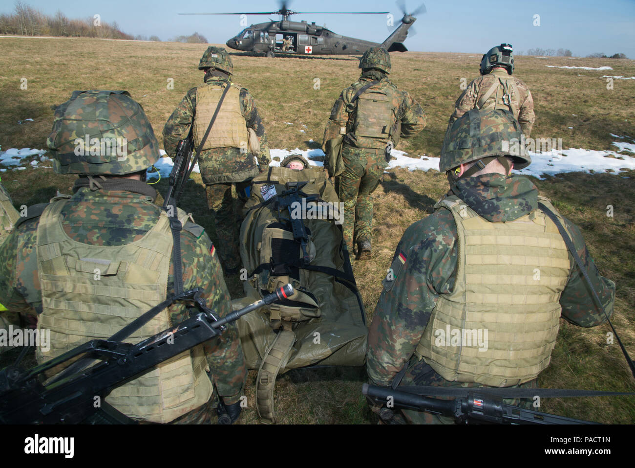 Deutsche Soldaten tragen ein Patient auf einem Feld in Richtung auf eine Bahre warten auf Blackhawk Hubschrauber während Tactical Combat Casualty Care Kurs, dass multinationale Soldaten aus NATO-Ländern die Teilnahme an der Internationalen Schulungszentrum, Train the Trainer Kurs, in dem die Hälfte der Teilnehmer Tactical combat Casualty care Lernen und die andere Hälfte Lernen, die Bekämpfung der Unfall- Kurs zu unterrichten. Das Training wurde von General Staufer Kaserne, Pfullendorf, Deutschland, 16. März 2016 (in den USA durchgeführt. Armee Foto von visuellen Informationen Spezialist Martin Greeson/Freigegeben) Stockfoto