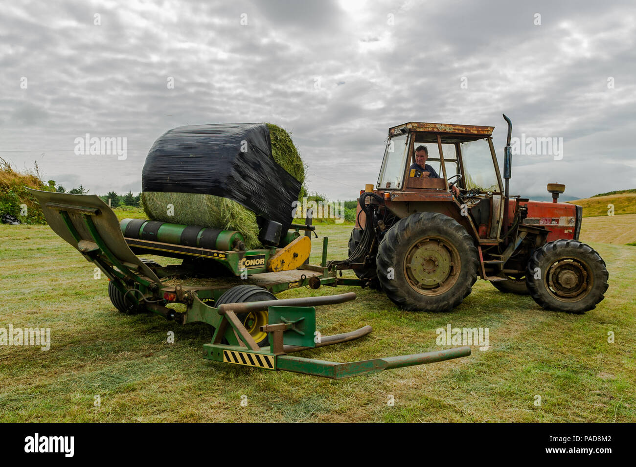 Ballydehob, West Cork, Irland. 22. Juli, 2018. Hollum basierte Landwirt Noel Station wickelt eine silage Kaution auf einem anderen sehr heißen Tag in Irland. Das Wetter ist wechselhaft im Laufe der nächsten Tage mit Regen Prognose für die ganze Woche. Die Temperaturen an den hohen Teens fallen/Low 20 Celsius. Credit: Andy Gibson/Alamy Leben Nachrichten. Stockfoto