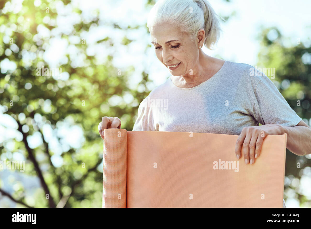 Ältere Frau mit einem Yoga Matte konzentriert Stockfoto