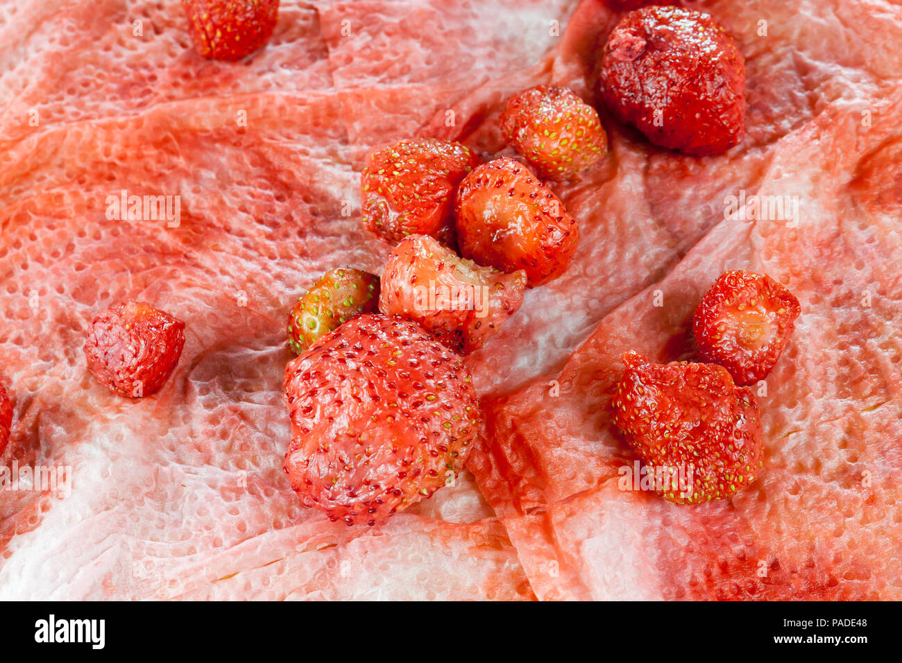 Alte zerknitterte Erdbeere liegen auf einem schmutzigen Papierserviette in Erdbeersaft, Nahaufnahme im Frühjahr Stockfoto