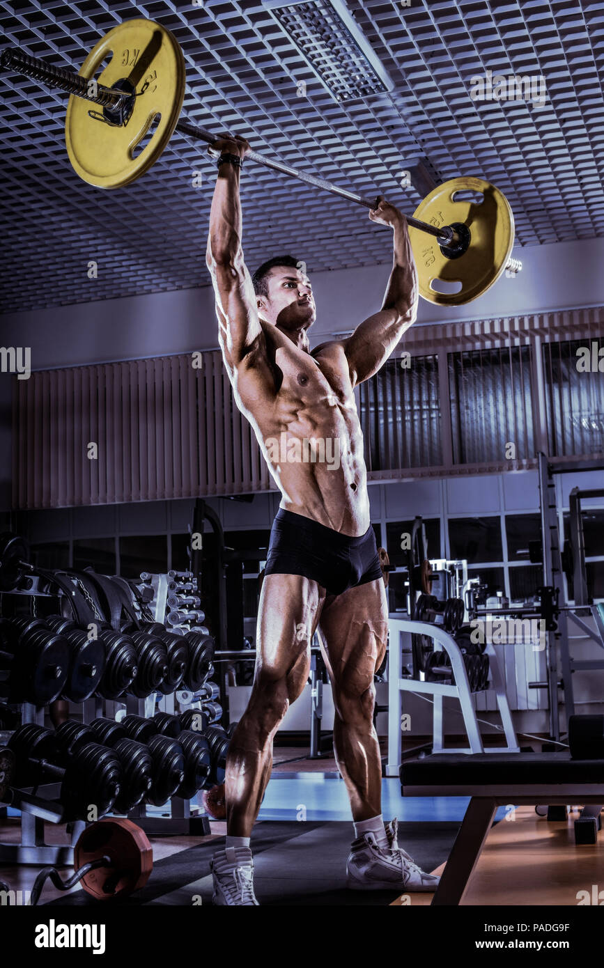 Guy Bodybuilder, Übung mit Gewicht in der Turnhalle ausführen, vertikale Foto, blau, violett Ton Stockfoto