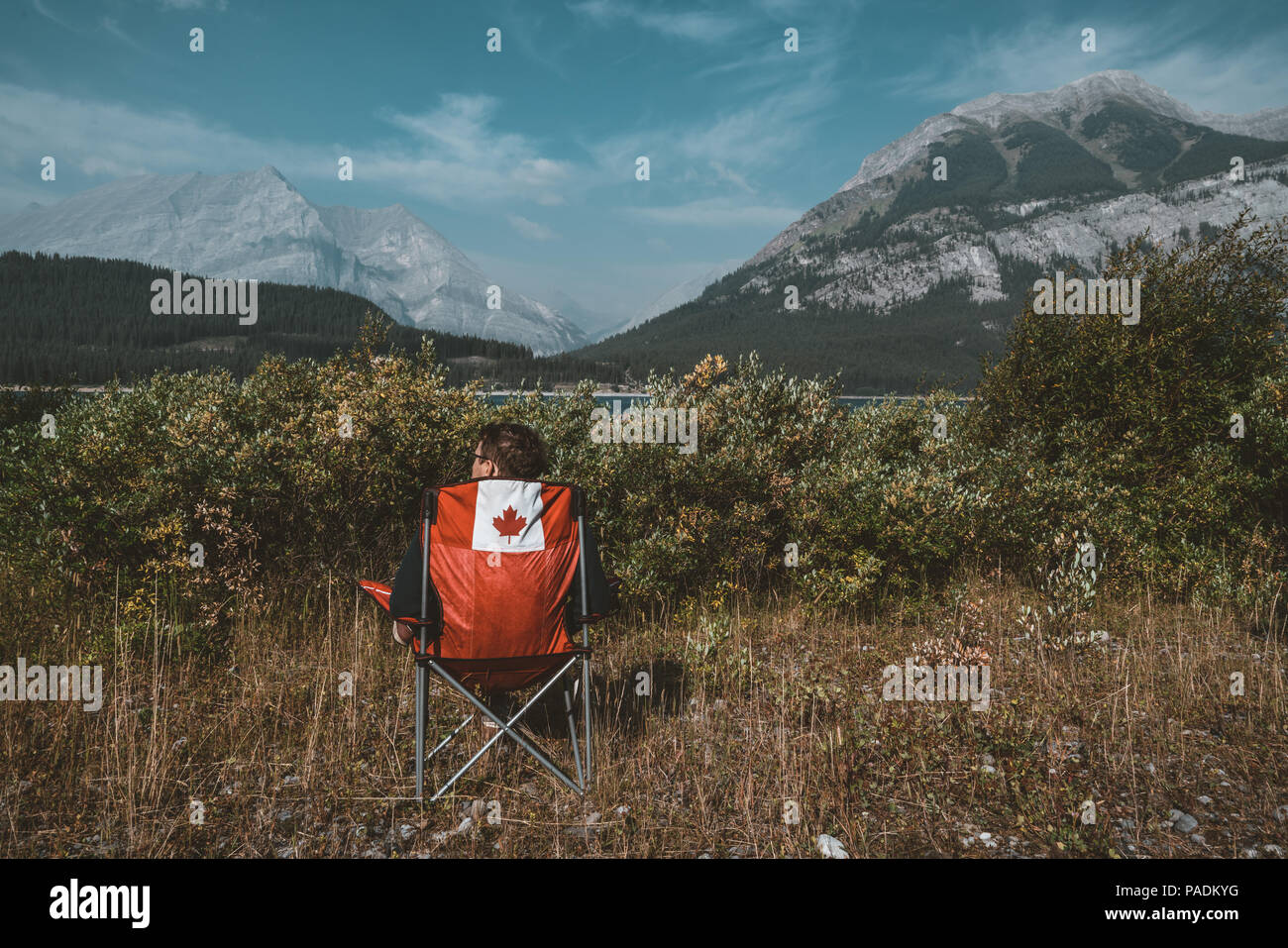 Roten Stühlen mit Kanada logo mit Blick auf Wiesen und Berge mit See im Lower Kananaskis Lake, Kanada Stockfoto