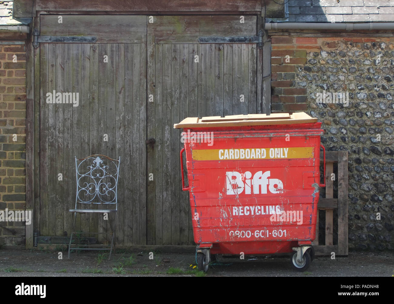 Schmutzig und verschlissen roten Biffa Papierkorb im Hof der Farm Shop Stockfoto