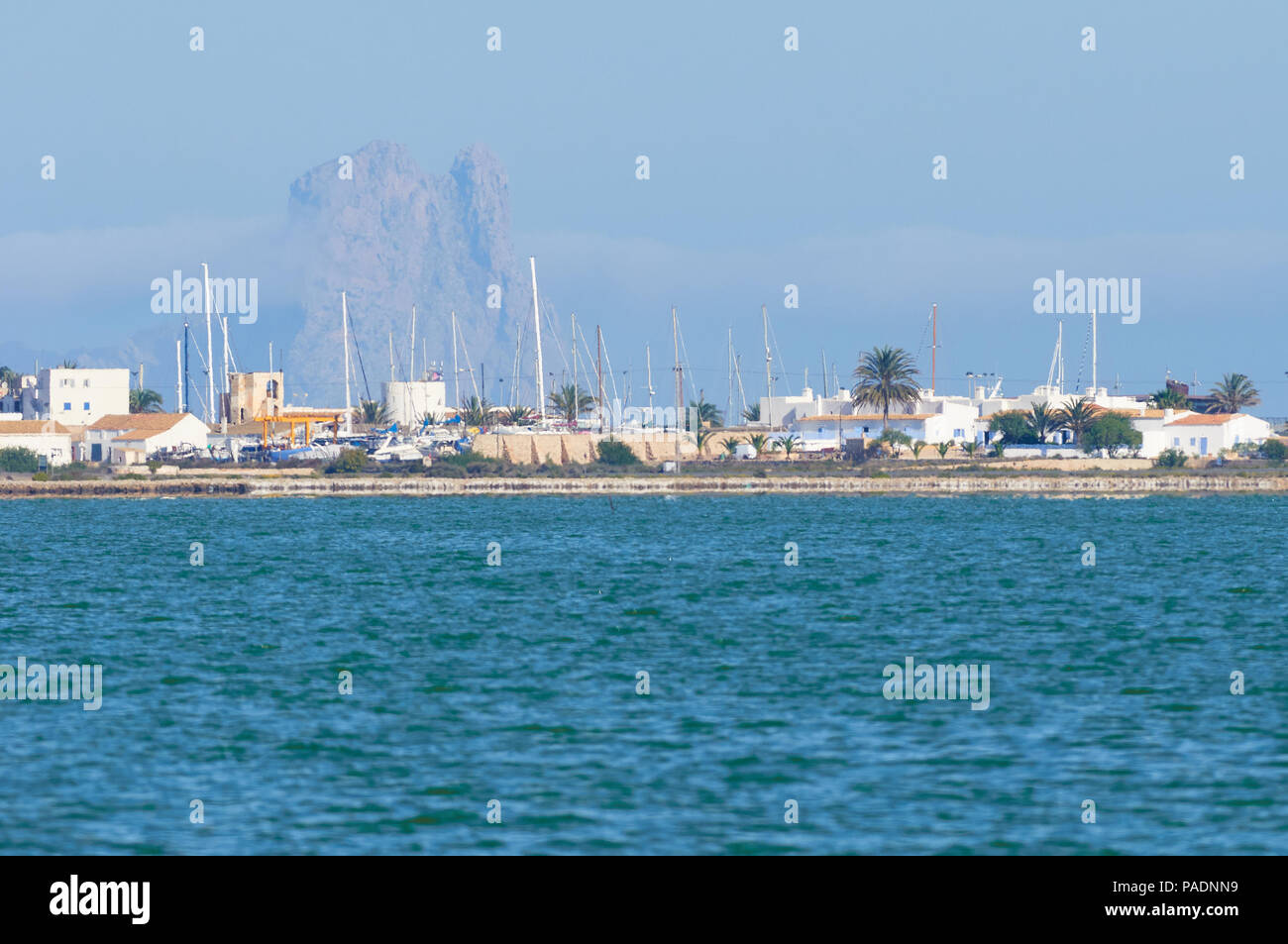 La Savina Ansicht mit Segel Schiffe Masten in Port mit Es Vedrá Inselchen im Hintergrund vom Estany Pudent (Ses Salines Natural Park, Formentera, Spanien) Stockfoto