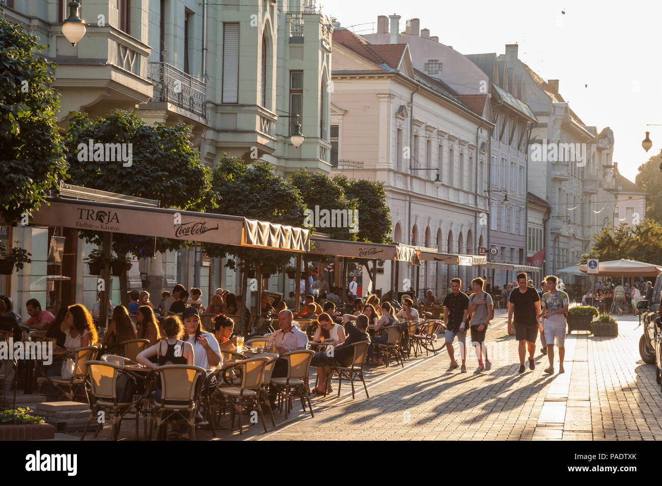 SZEGED, UNGARN - Juli 2, 2018: Junge Menschen zu Fuß auf einer Fußgängerzone in Szeged, in Südungarn, mit anderen Personen sitzen auf Tabellen in Cafés Stockfoto